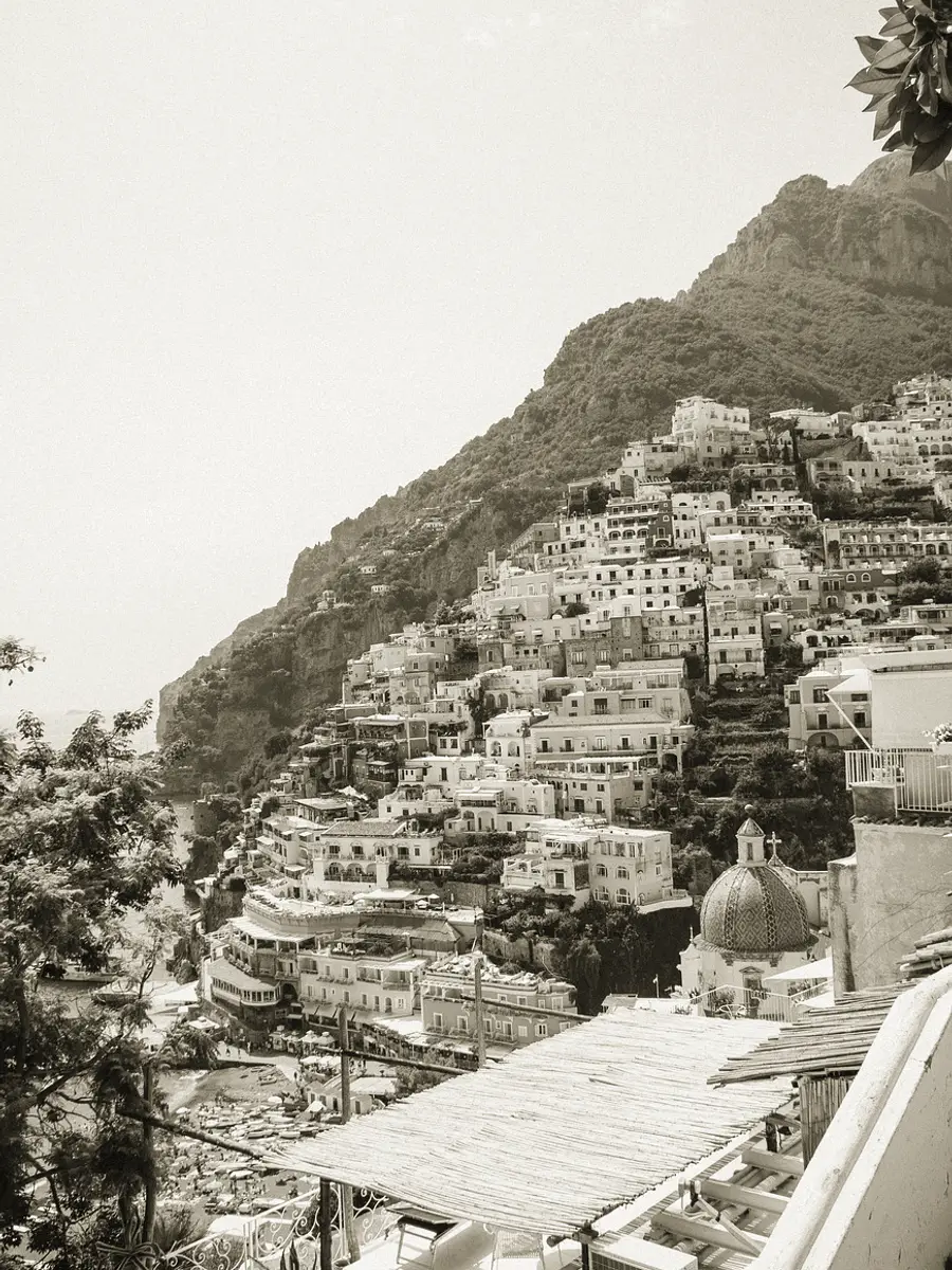 A steep hillside town of stacked pale houses descending in terraces to the water